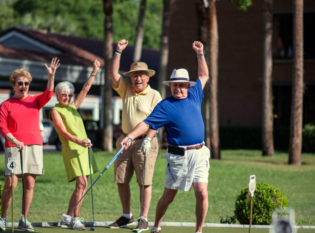 group of senior friends playing golf at their senior community celebrate a hole-in-one