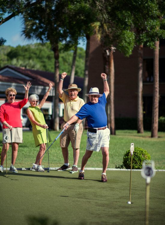 group of senior friends playing golf at their senior community celebrate a hole-in-one