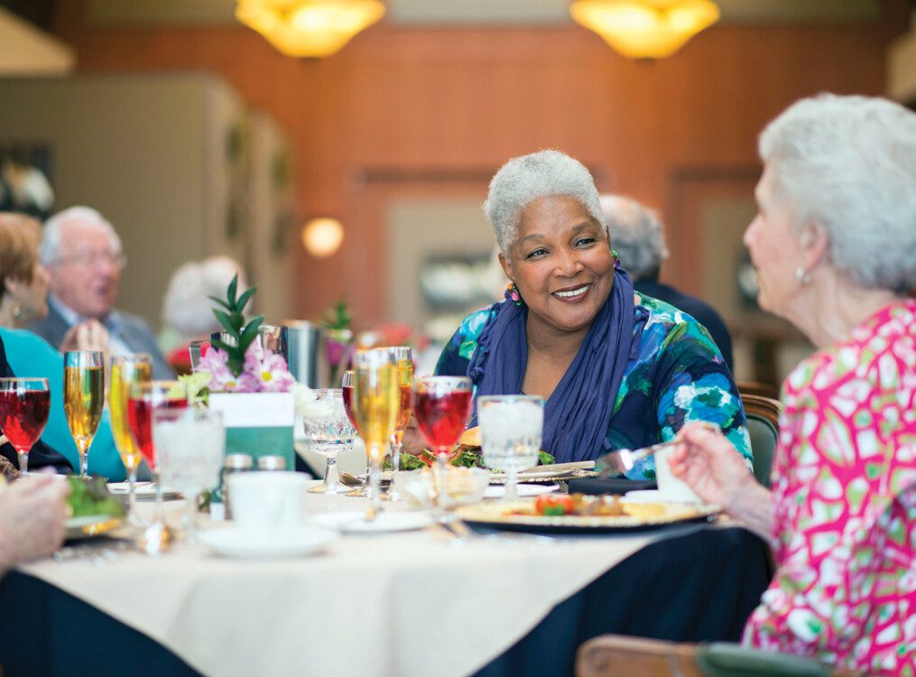 senior woman smiles at her companions during an elegant dinner at her senior living community