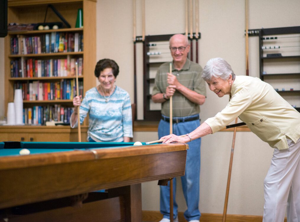 group of seniors play a game of pool together at their senior living community