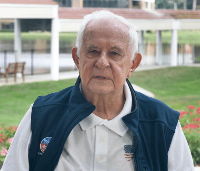 Senior man (Stan Goldstein) speaks and stands outdoors during interview