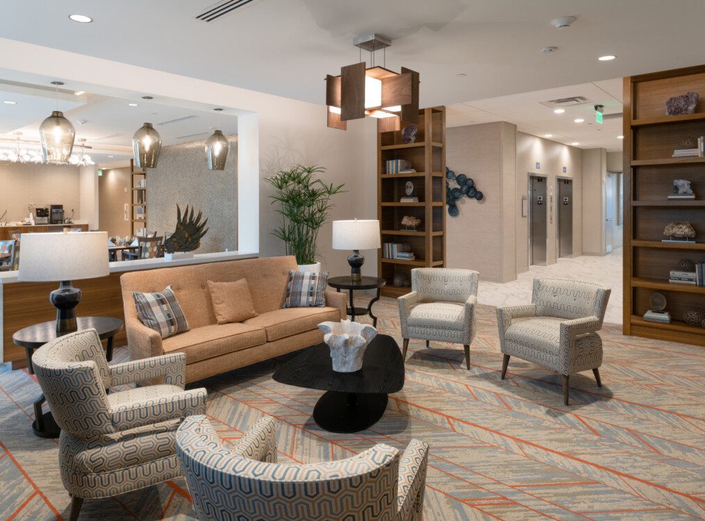 spacious interior lounge area at Village on the Green Senior Living Community with bookshelves and seating