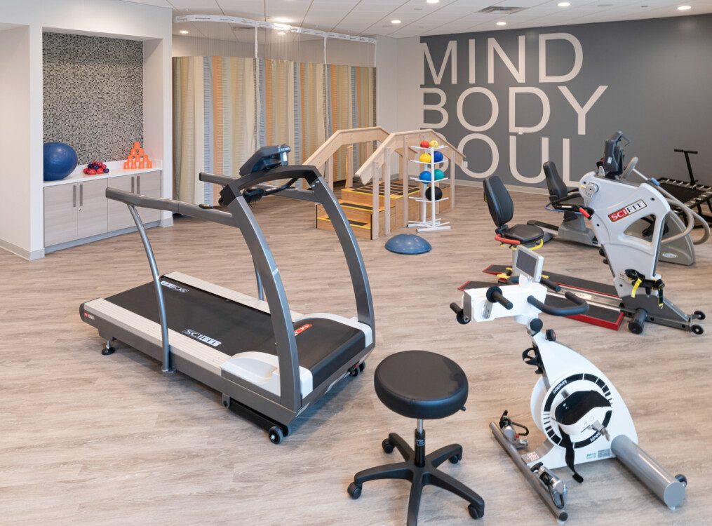 fitness equipment including stationary bikes and treadmill in physical therapy room at Village on the Green Senior Living Community