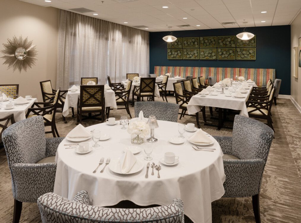 elegant formal dining room with tables and chairs at Village on the Green Senior Living Community