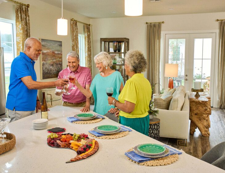 group of senior friends enjoy wine and dinner together in one of the villas at Village on the Green Senior Living Community