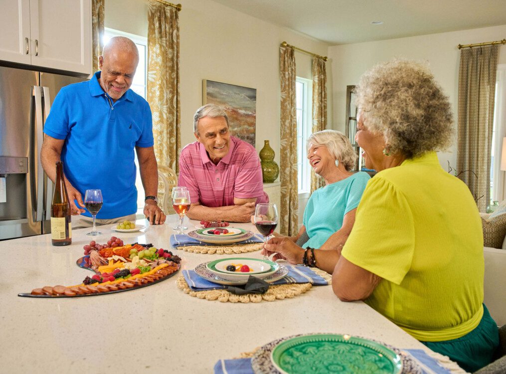 group of senior friends enjoy wine and dinner together in one of the villas at Village on the Green Senior Living Community