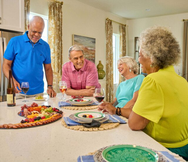 group of senior friends enjoy wine and dinner together in one of the villas at Village on the Green Senior Living Community