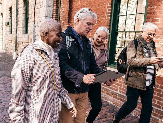 Group of four older adults exploring a city while on vacation.