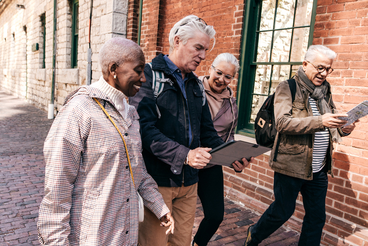 Group of four older adults exploring a city while on vacation.