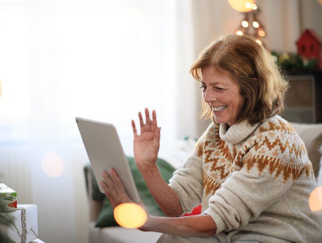 Senior woman smiling as she talks via video chat on her tablet.