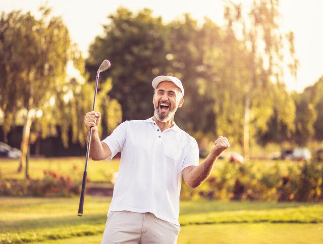 Man happily cheering as he scores a hole-in-one.