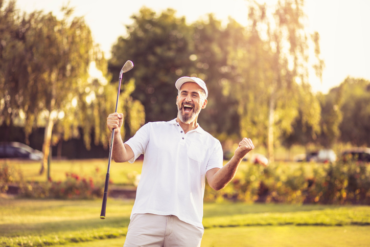 Man happily cheering as he scores a hole-in-one.