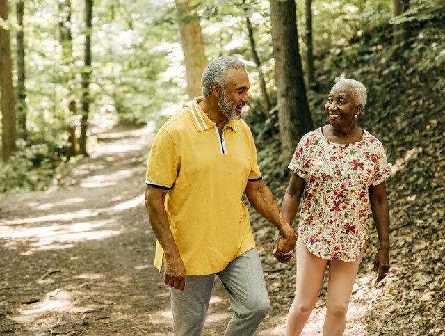 Senior couple holding hands as they hike together.