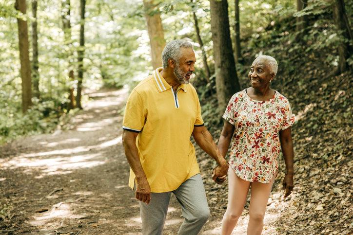 Senior couple holding hands as they hike together.
