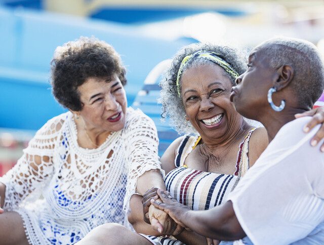 Three multiracial senior women on lounge chairs talking
